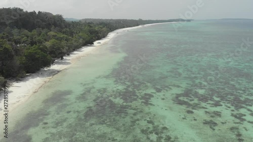 Aerial: uncontaminated coastline tropical beach caribbean sea coral reef atoll in the Kei Islands Maluku Moluccas Indonesia scenic travel destination. Native cinelike D-log color profile photo