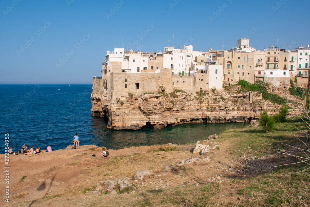 Panoramic city skyline with white houses of Polignano a Mare, town on the rocks, Puglia region, Italy, Europe. Traveling concept background with blue Mediterranean sea with tourists and nature