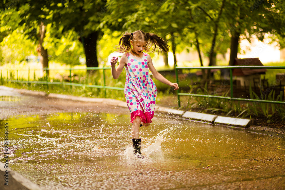 Little kid girl runs through a puddle. summer outdoor Little kid girl runs through a puddle. summer outdoor