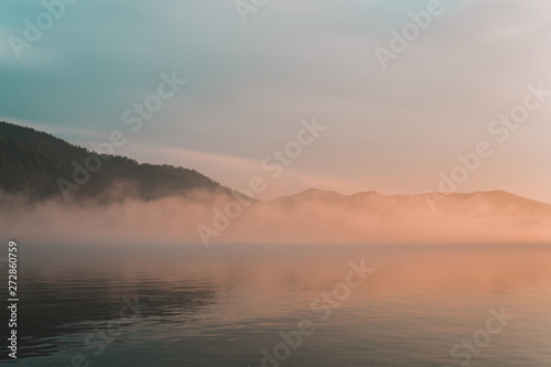 sunset with fog over the lake. fog after rain over water.