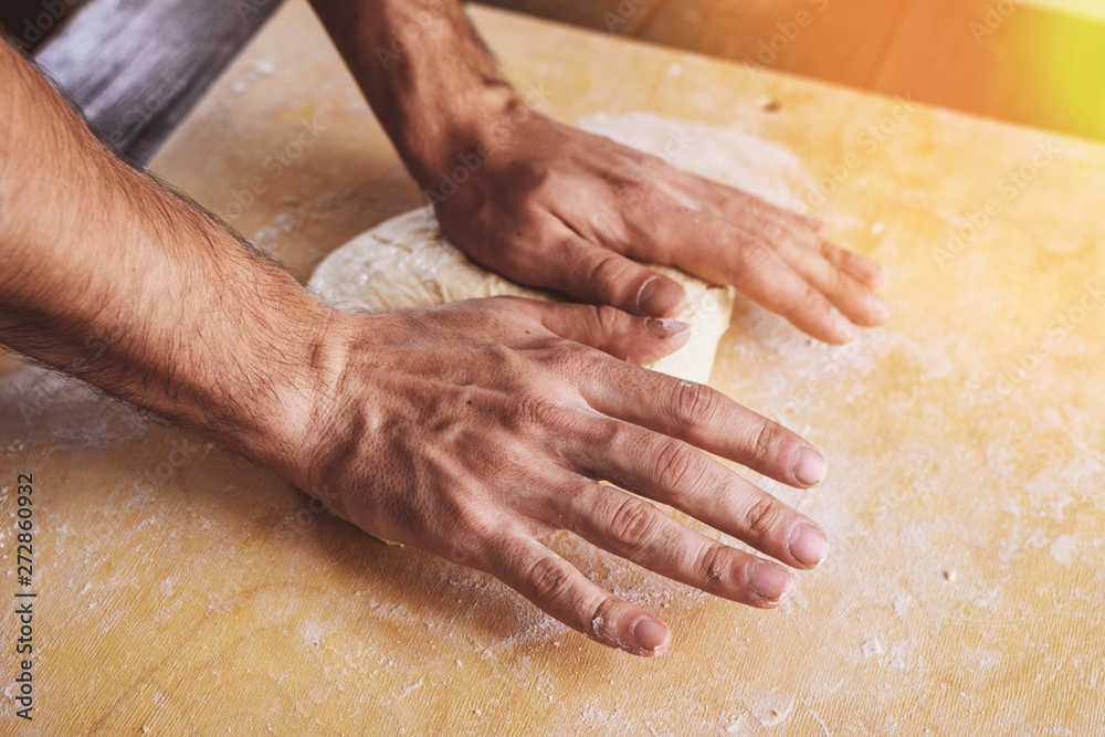 Close-up of men's hands roll out, prepare the basis for pizza