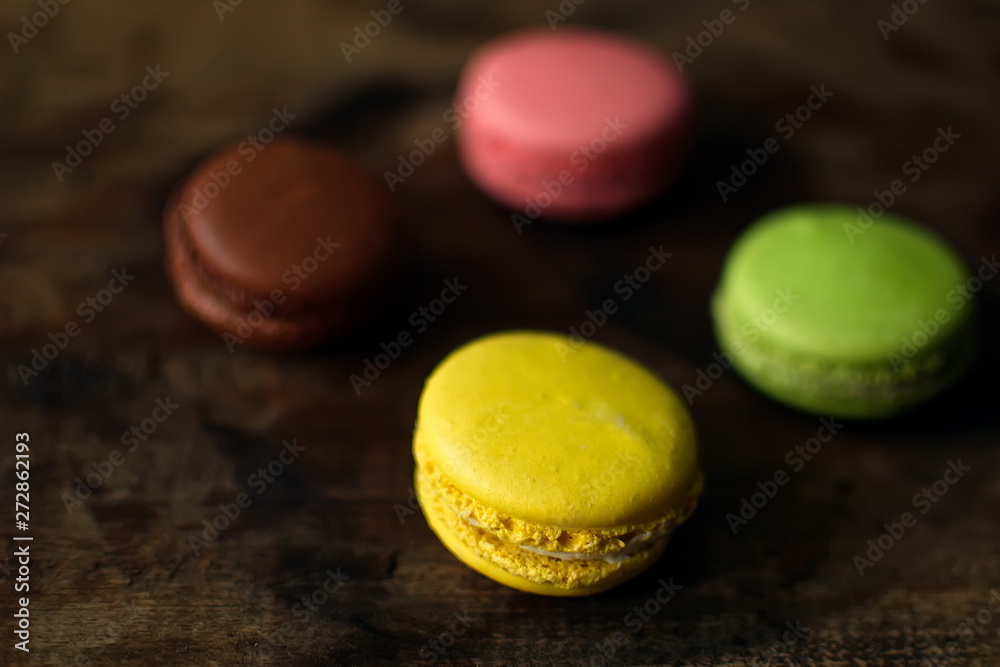 Multi-colored macaroons on a wooden tray. Pink, yellow and green macaroon. Multi-colored macaroons on a wooden tray. Pink, yellow and green macaroon.