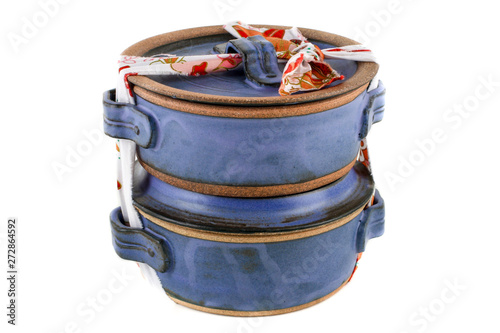 Elegant blue ceramic pot "marmita" with printed fabric strip, used as packed lunch isolated on white background.