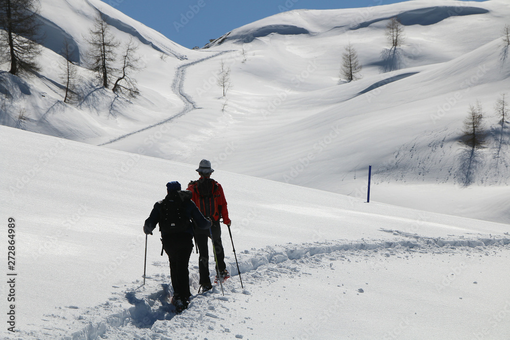 Hiking on snowshoes on a trail. Chamois, Valle D'Aosta, Italy.