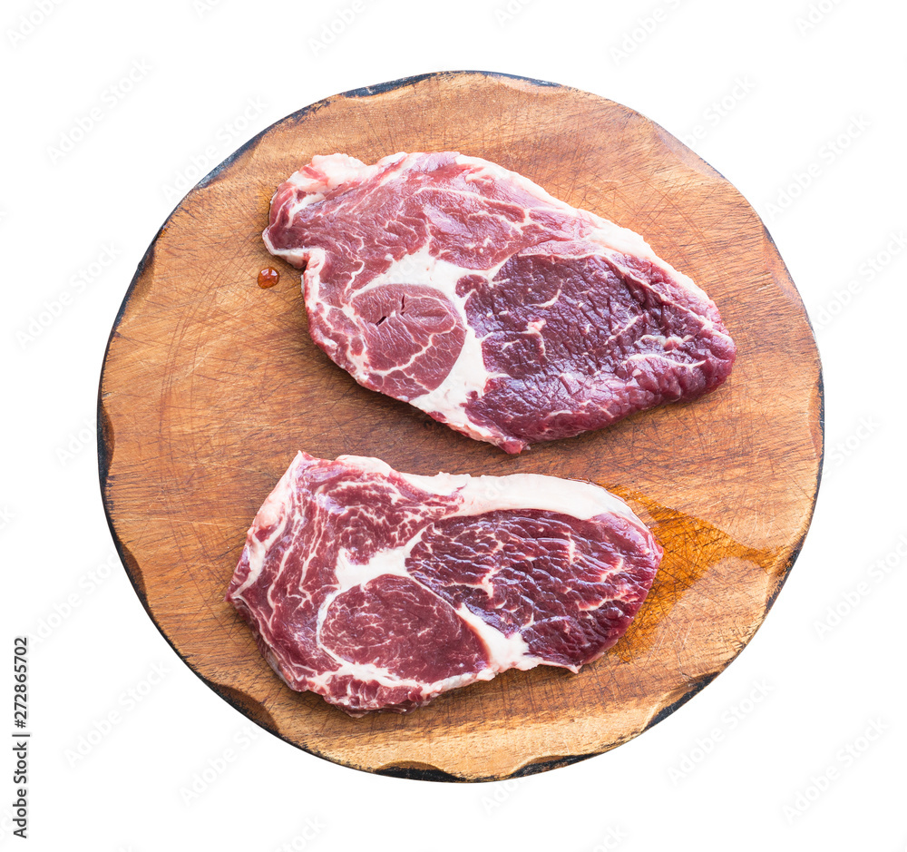 two raw marble beef steaks on wooden cutting board two raw marble beef steaks on wooden cutting board