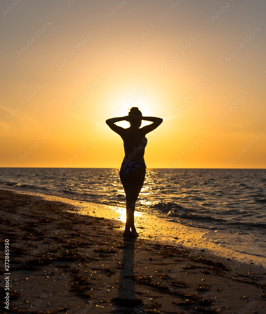 woman practicing yoga on the beach at sunset