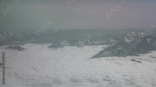 Aerial view of snowy mountains and clouds. View from the plane on a mountain folds. The tops of the mountains covered with snow view from the window of the plane. Alborz or Alburz, Elburz or Elborz photo