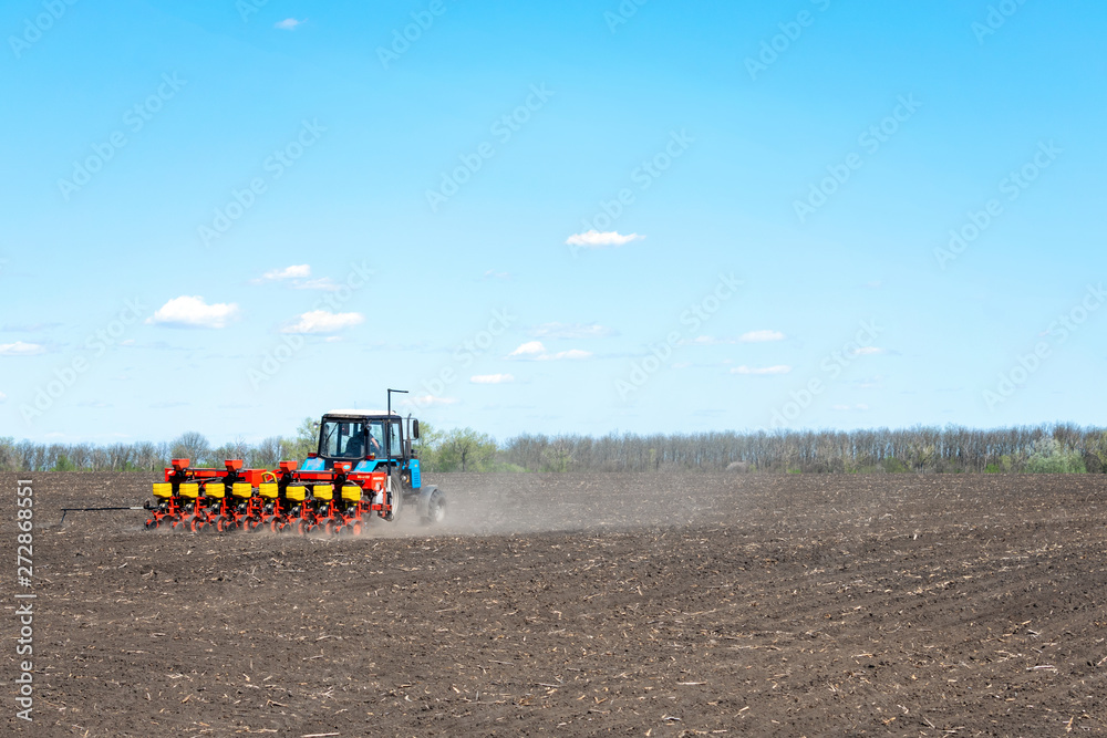 Kropivnitskiy, Ukraine – 12 may, 2018: tractor sows corn on a plowed field on a sunny day. tractor seeding - sowing crops at agricultural fields in spring