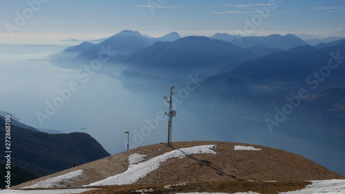 View of Lake Garda from the top of Baldo. Beautiful blue water, sky and sharp mountain peaks (Alps and Dolomites)