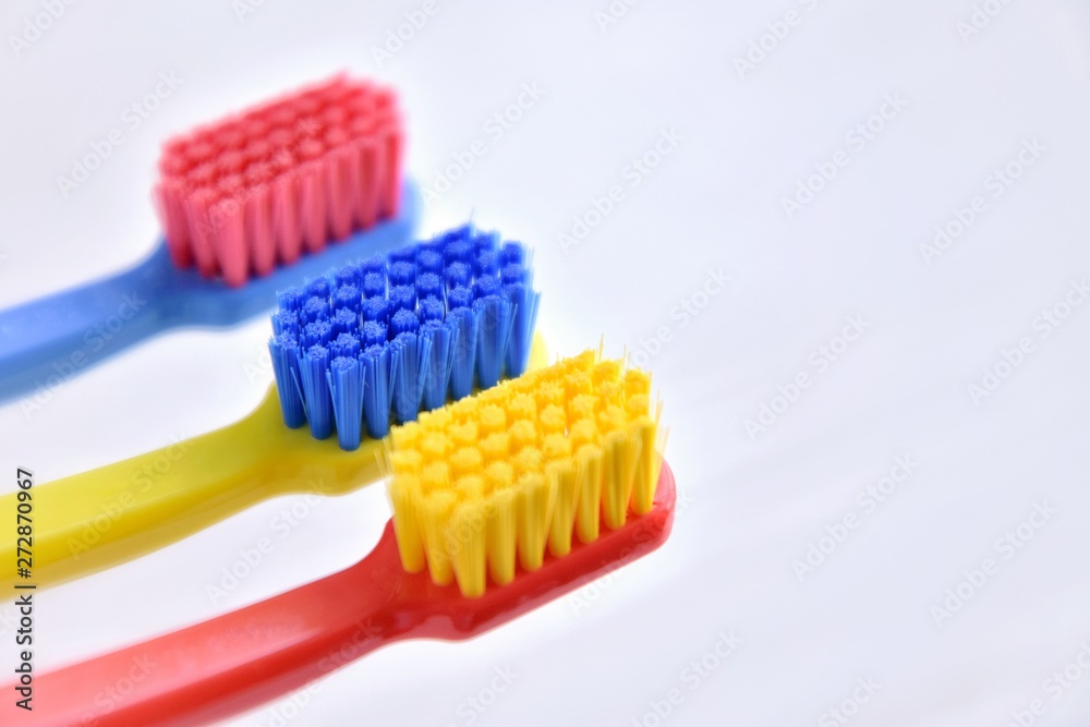 Three colorful toothbrush with selective focus on blurred neutral background. Plastic toothbrushes with multicolor bristles, soft focus. Manual toothbrush for daily morning routine. Dental healthcare