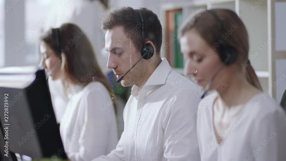 Portrait young people woman man operator taking calls use computer smile in call center office business worker corporate headset job man service group finance sunshine phone close up slow motion Portrait young people woman man operator taking calls use computer smile in call center office business worker corporate headset job man service group finance sunshine phone close up slow motion