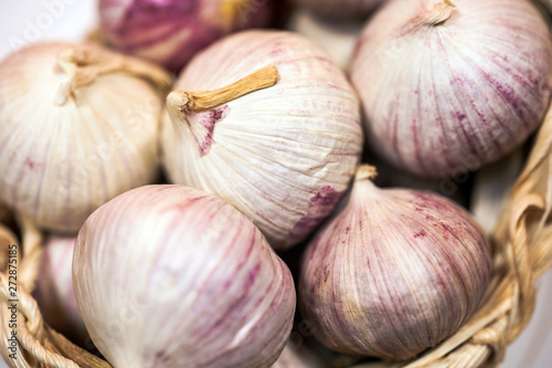 Garlic in a wicker basket, on a white background. Dried French garlic. Red garlic.