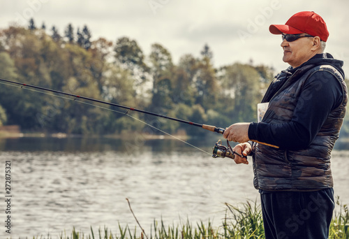 Elderly man enjoys fishing by the river in the summer.