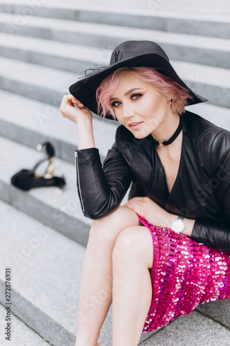 Street urban portrait of young hipster caucasian stylish sexy cheerful gorgeous woman in black suit and pink dress smiling. Happiness, fashion, beauty, freedom concept. Grey color background