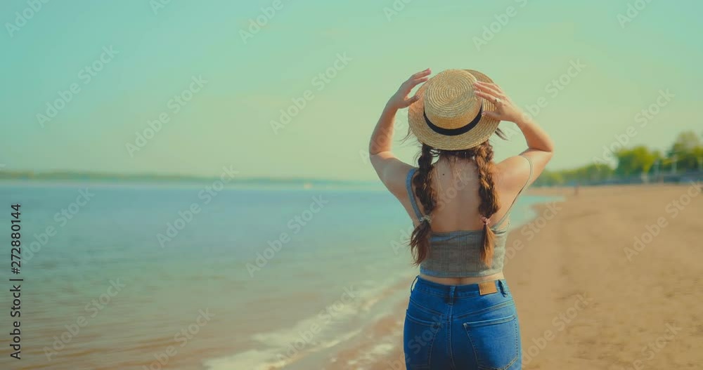 Woman in a hat is walking along the river bank. Back view. Woman in a hat is walking along the river bank. Back view.