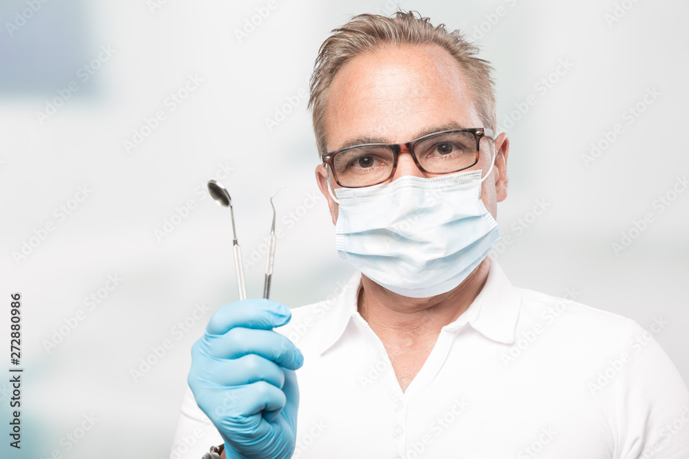 dentist with gloves and face mask holding a dental tool dentist with gloves and face mask holding a dental tool