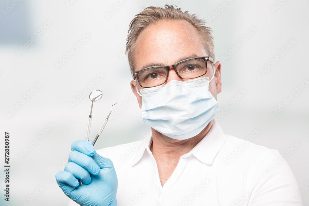 dentist with gloves and face mask holding a dental tool dentist with gloves and face mask holding a dental tool