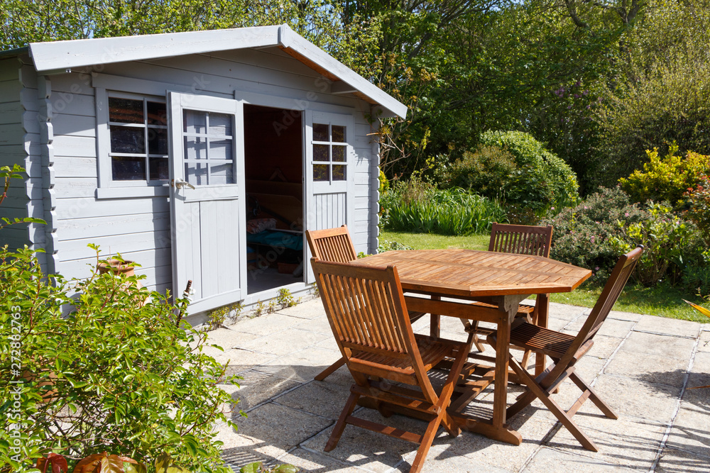 Shed with terrace and wooden garden furniture during spring