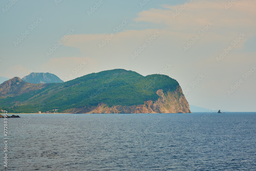 view of the sea against the backdrop of the island in the village of Petrovac in the afternoon with clouds on the sky and an island in the distance.
