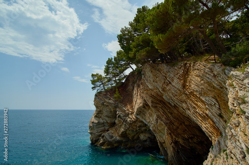 rocky cliff with trees in the village of Petrovac, overlooking the sea during the day.