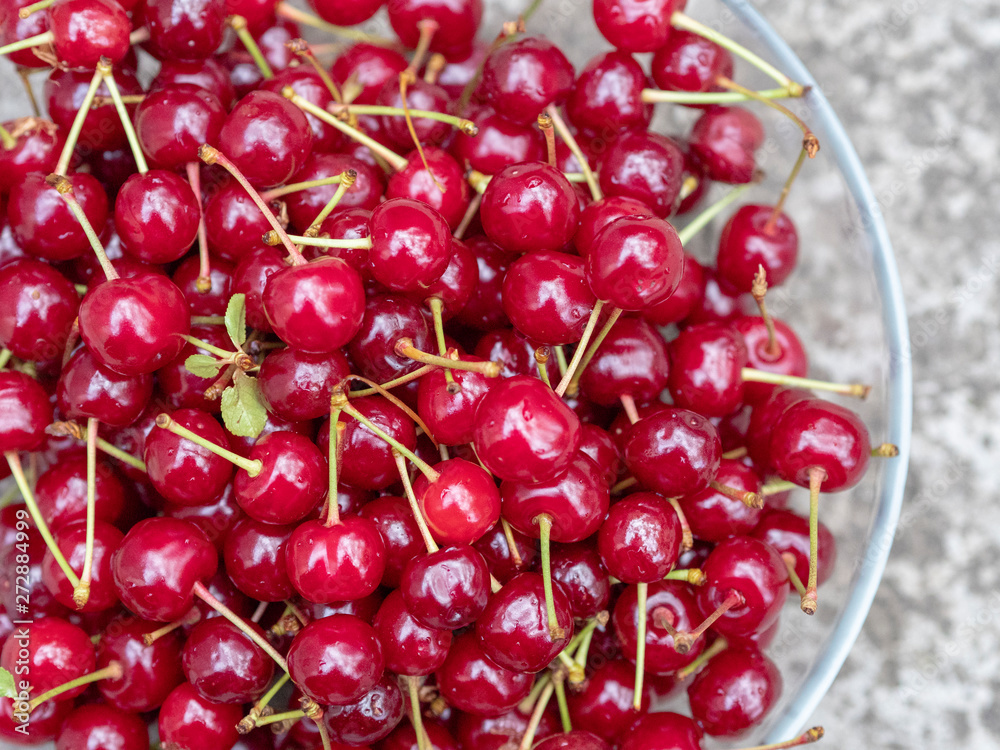 Ripe juicy red cherries in a transparent plate. A rich harvest of healthy berries. Natural vitamins. Photo view from the top. Ripe juicy red cherries in a transparent plate. A rich harvest of healthy berries. Natural vitamins. Photo view from the top.