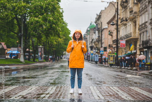 woman in the middle of the street crossing road in yellow raincoat © phpetrunina14