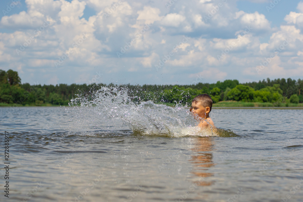 Adolescent boy splashing while swimming in the lake