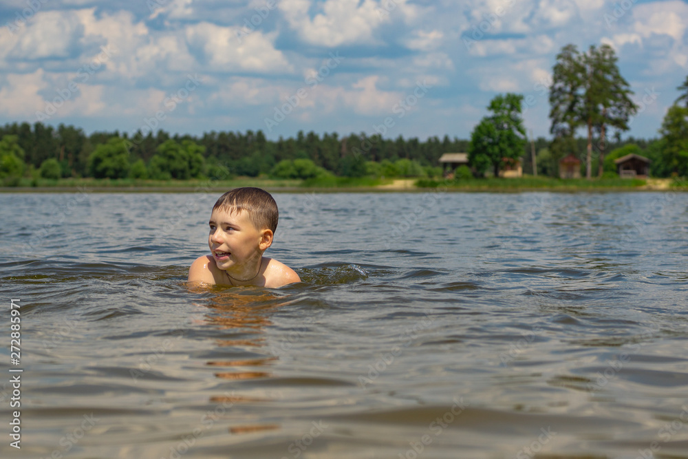 Adolescent boy swims alone in the lake