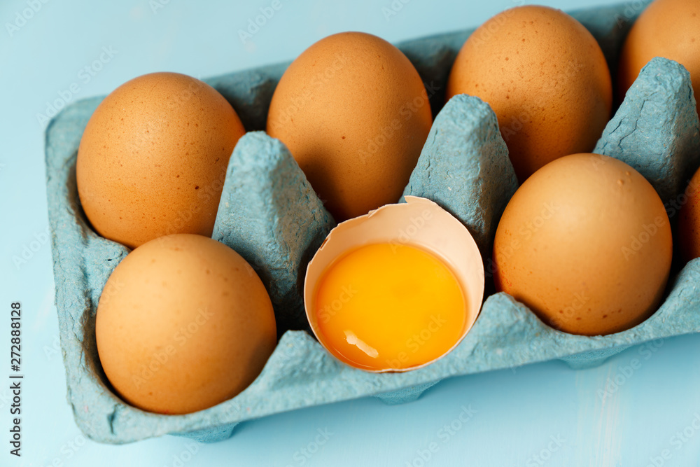 Close-up view of raw organic chicken eggs in a blue carton box. Blue background, high resolution Close-up view of raw organic chicken eggs in a blue carton box. Blue background, high resolution