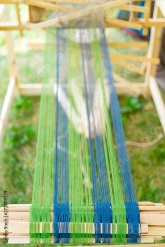 Blue and green threads in an old wooden machine.