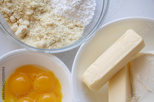 Dry Ingredients, Butter and Eggs. Almond flour and confectionery sugar, butter and cracked eggs create a nice texture. Baking ingredients background.