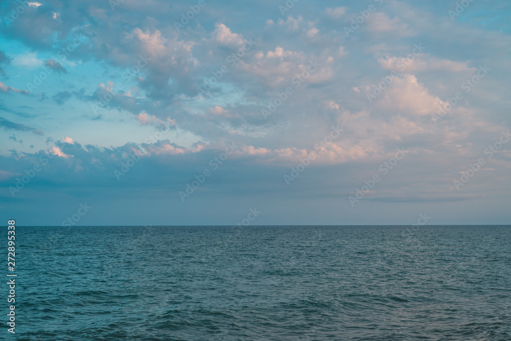 Sea view, ocean background. Clear calm sea with clouds on the sky.