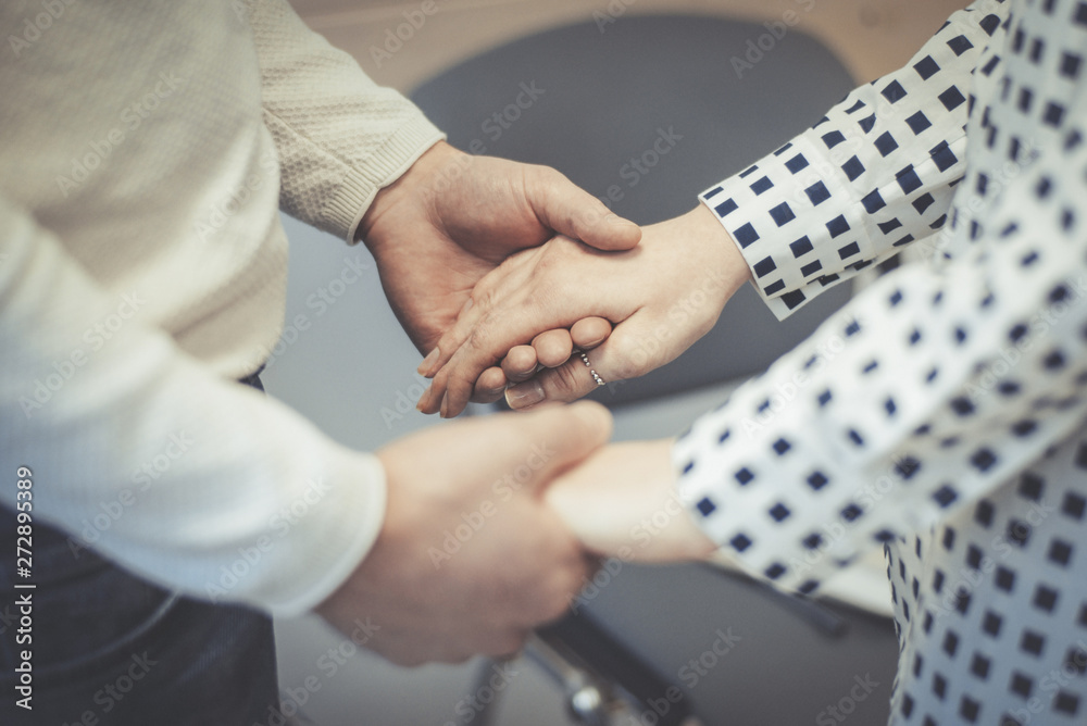 Obraz premium A man and a woman opposite each other hold hands. The concept of union, dialogue, confidential conversation between people.