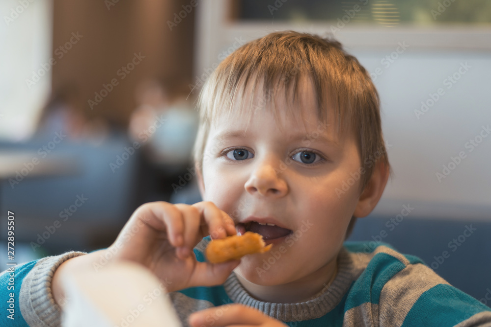 The little boy eats in a fast food restaurant. The little boy eats in a fast food restaurant.