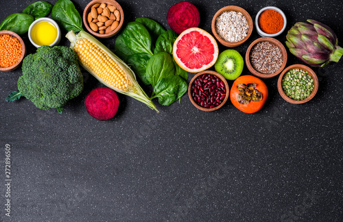 Selection of healthy food fresh vegetables and fruit against black stone background. Concept of clean eating, vegetarian and vegan food and cuisine, lifestyle, diet, and fitness