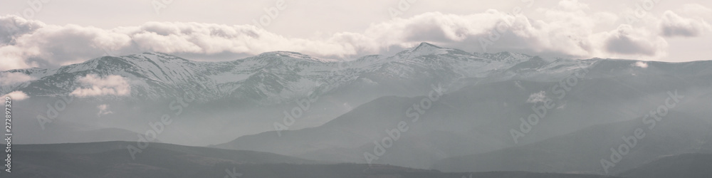 Mountains covered in winter snow and low clouds with naked rocks. Beautiful nature scenery in winter. Panoramic view, North Spain.