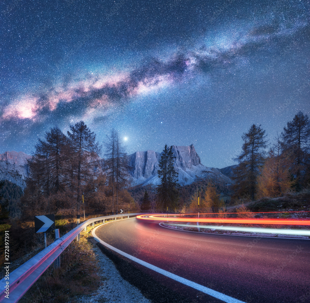 Milky Way over mountain road. Blurred car headlights on winding road in ...