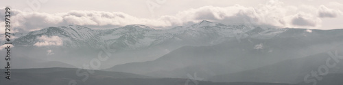 Fototapeta Naklejka Na Ścianę i Meble -  Mountains covered in winter snow and low clouds with naked rocks. Beautiful nature scenery in winter. Panoramic view, North Spain.