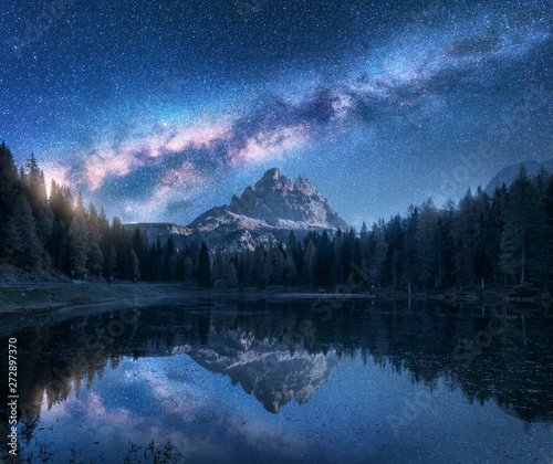 Fototapeta Naklejka Na Ścianę i Meble -  Milky Way over Antorno lake at night. Summer landscape with alpine mountains, trees, blue sky with milky way and stars, beautiful reflection in water, high rocks. Dolomites, Italy. Space and nature