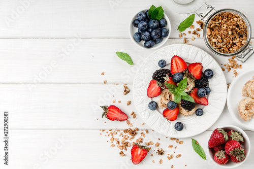 Healthy breakfast with granola, fruits, berries on white background.