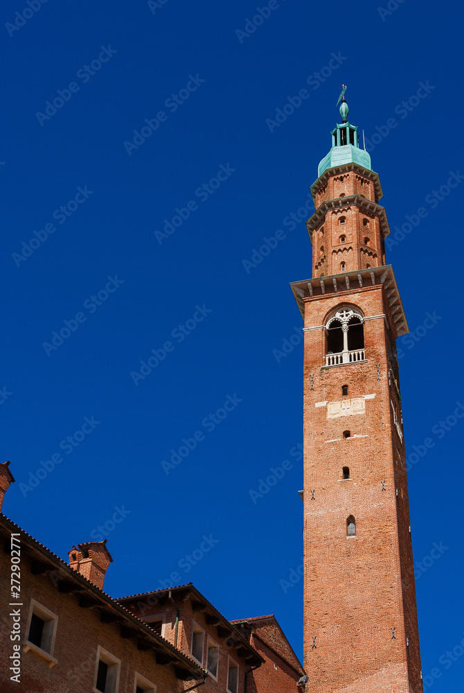 Bissara Tower rises above historic center tradtional red tile roofs and old chimney. Completed in the 15th century, it's the tallest building in Vicenza (with copy space)