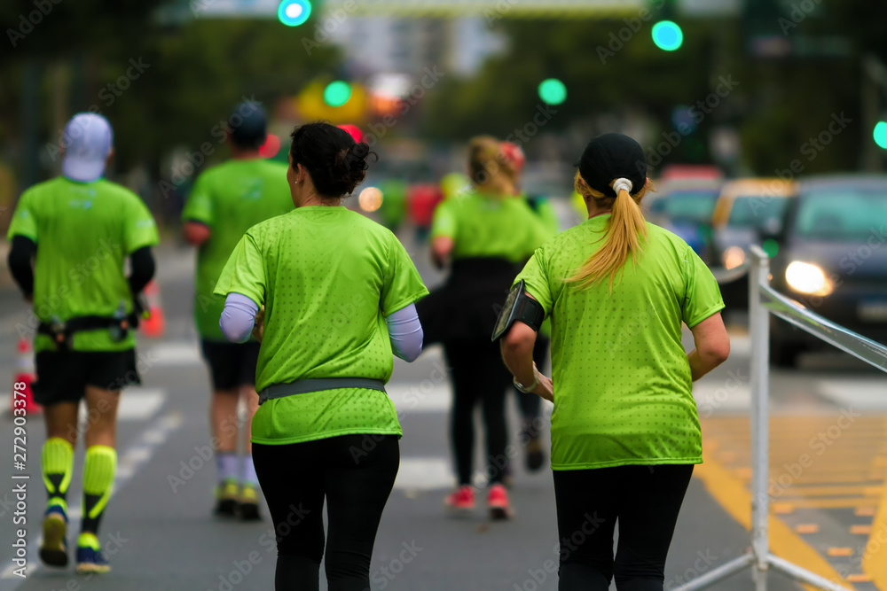 Group of men and women seen from behind run a marathon