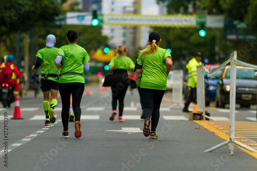 Group of men and women seen from behind run a marathon