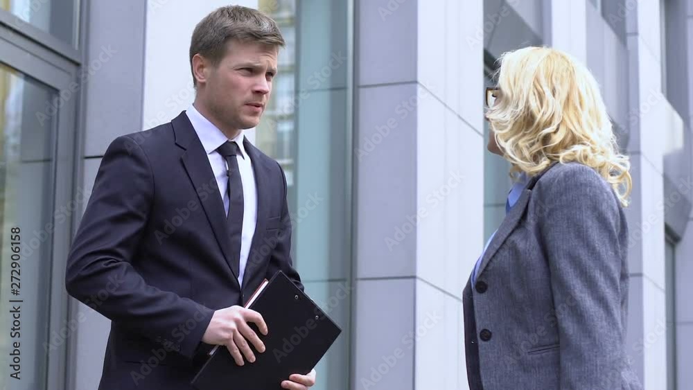 Young man catching up with elderly CEO on street, asking help in business