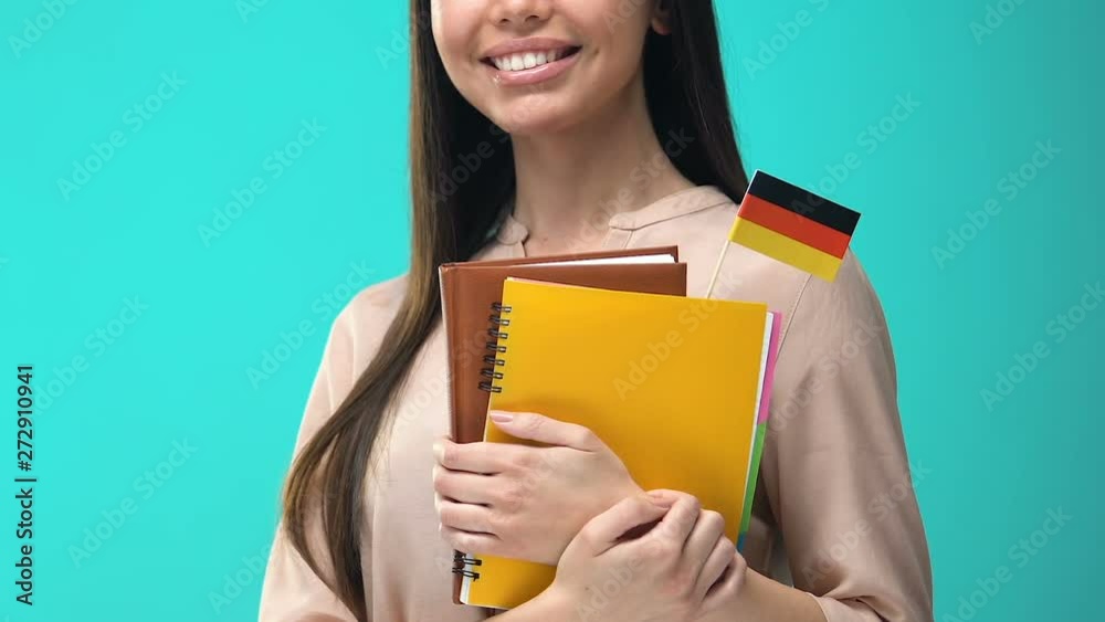 Joyful young woman holding German flag notebooks in hands, magistracy abroad Joyful young woman holding German flag notebooks in hands, magistracy abroad