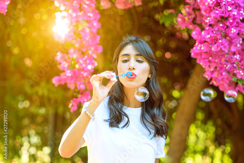Returning to nature to connect with the inner self. Happy beautiful young woman blowing soap bubbles outdoor.