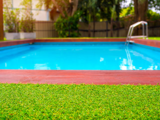 Close-up green grass on outdoor swimming pool background