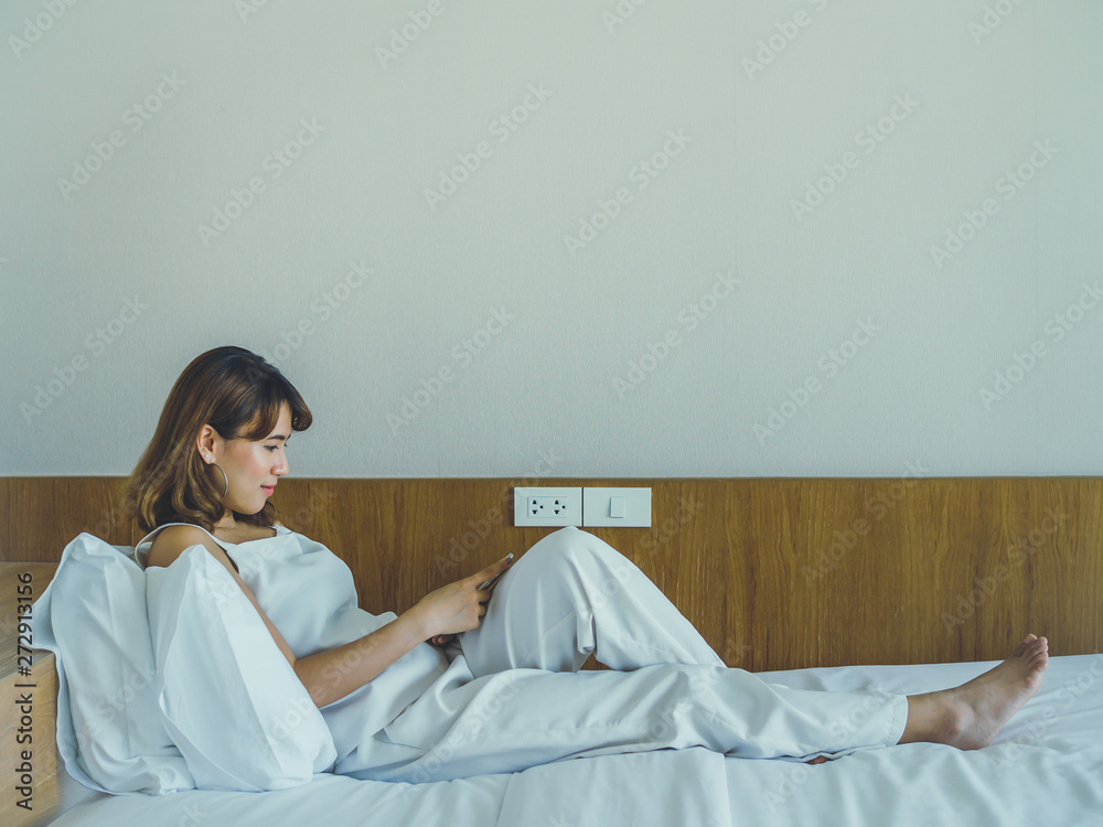 Beautiful asian woman smiling on the bed and using smartphone Beautiful asian woman smiling on the bed and using smartphone