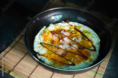 Fried eggs in a pan with sauce, onion, garlic and coriander.Crushed egg, Thai food