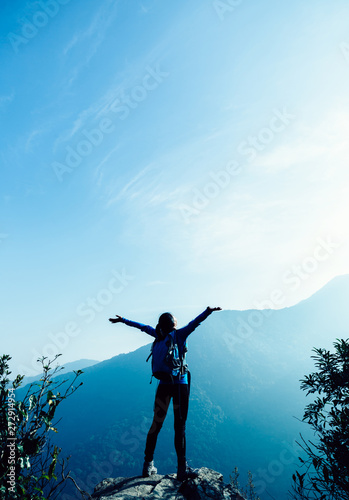 Successful hiker with arms outstretched on sunrise mountain top